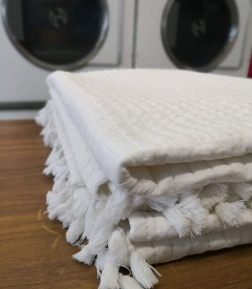 Folded clean Bedspread on folding table in laundry